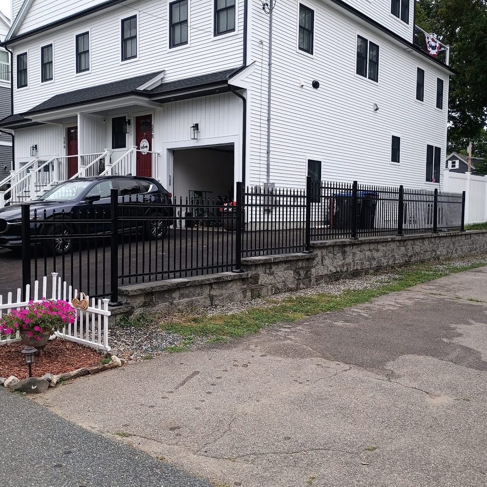 Black ornamental aluminum fence in front of a white colonial home