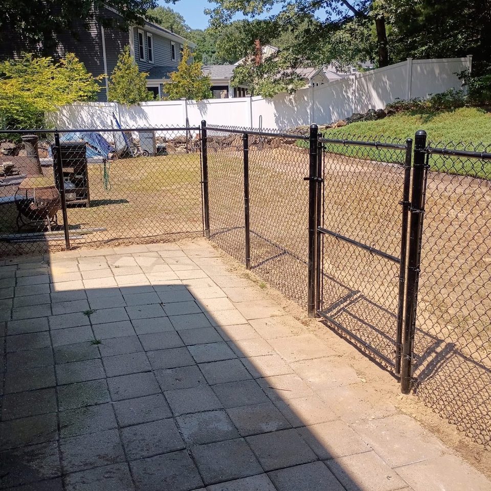 Black chain link fence and gate opening onto a patio