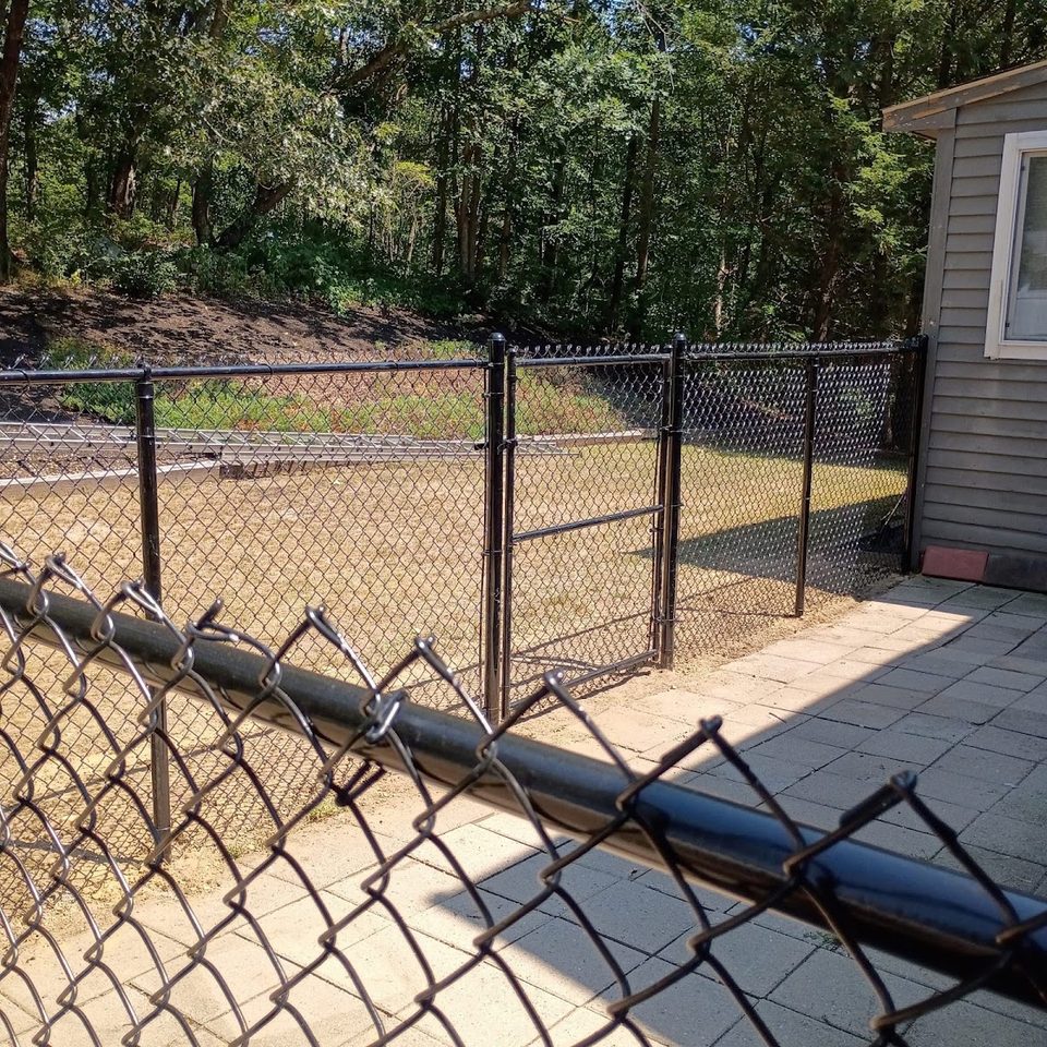 Black chain link fence enclosing a paved patio area