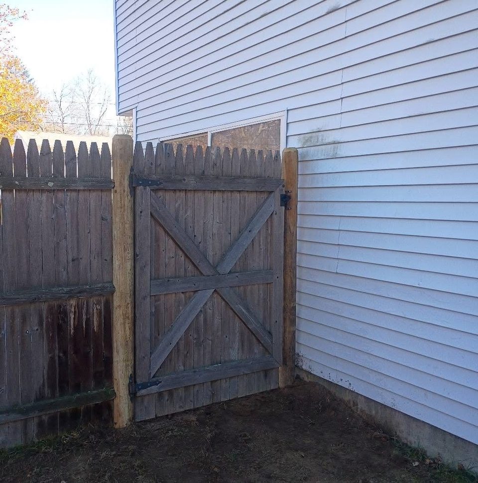 Diagonally braced wooden gate fitted beside a house wall