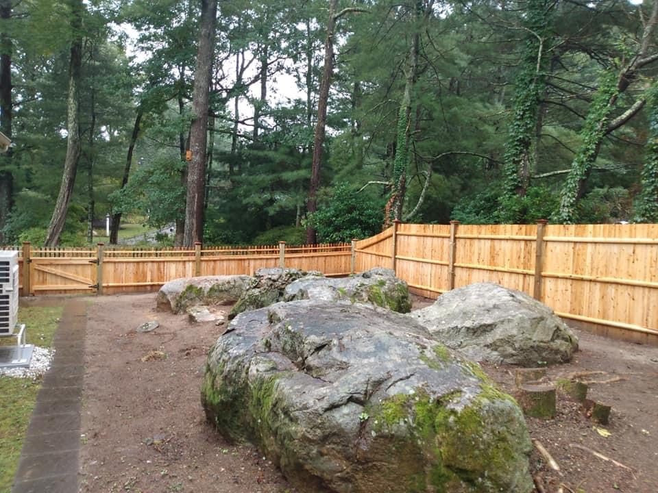 Cedar fence built around large landscape boulders in a back garden