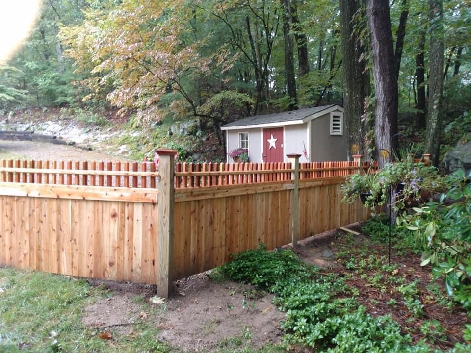 Cedar fence stepped down a sloping wooded boundary