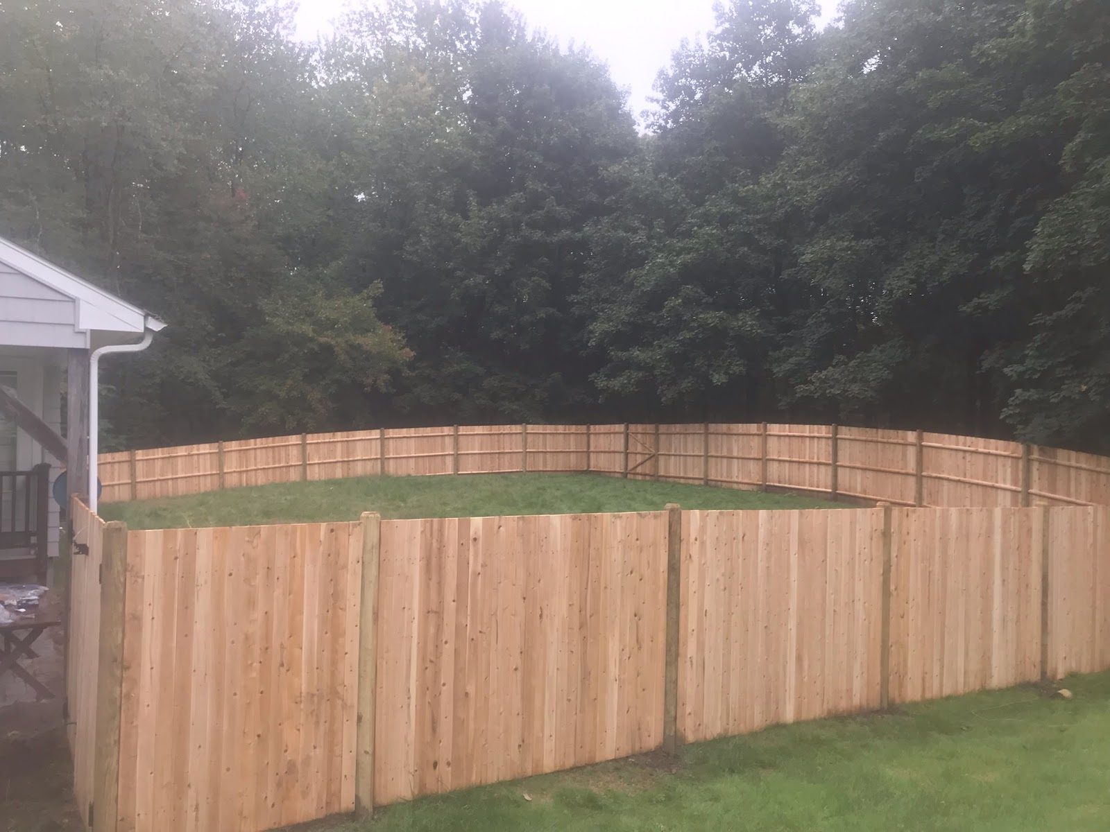 Long cedar stockade privacy fence running along a green back lawn
