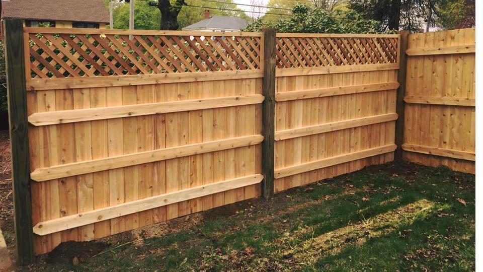 Close detail of a lattice-top cedar privacy fence and post cap
