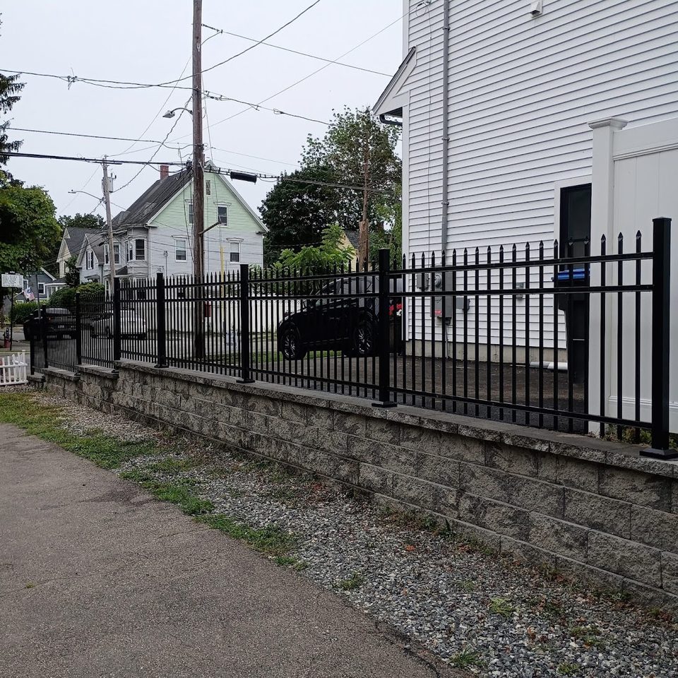 Ornamental aluminum fence mounted on a low stone retaining wall