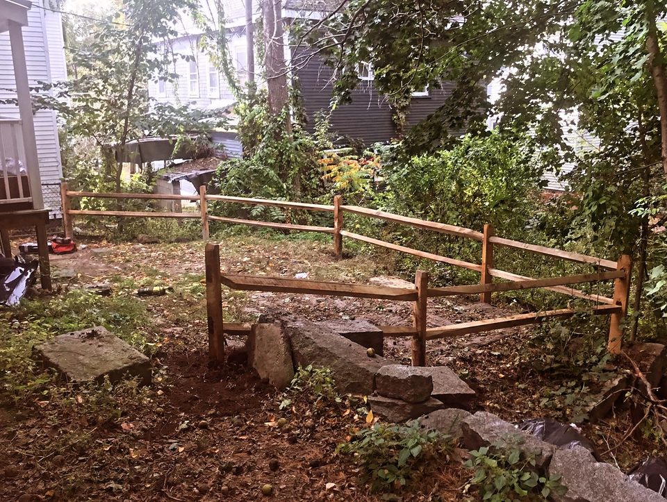 Rustic post and rail fence being rebuilt on a sloping bank