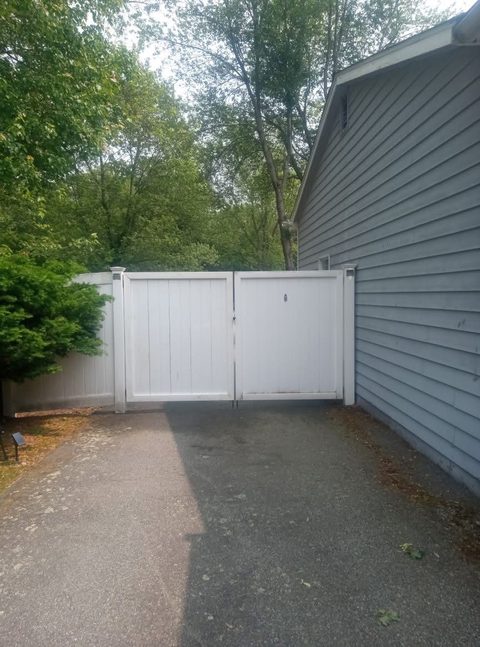 Vinyl double gate providing driveway access beside a garage
