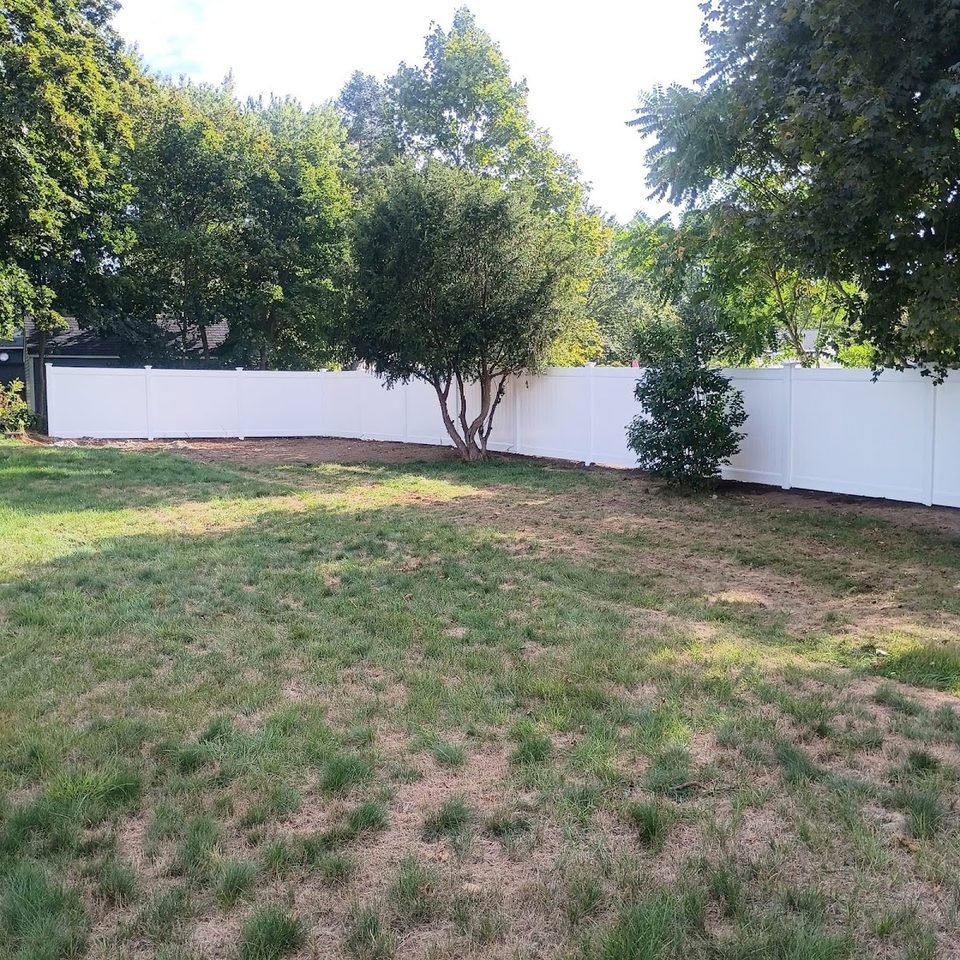 White vinyl fence across a wide open back lawn