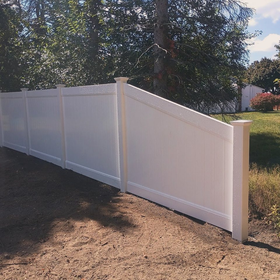 Newly installed white vinyl privacy fence on a levelled yard