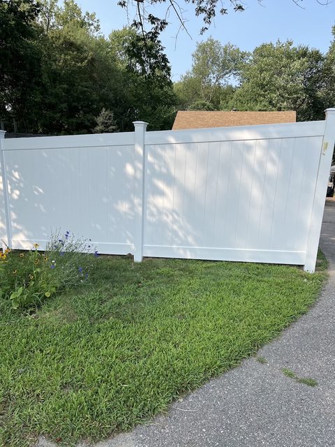 White vinyl privacy fence running beside a concrete walkway